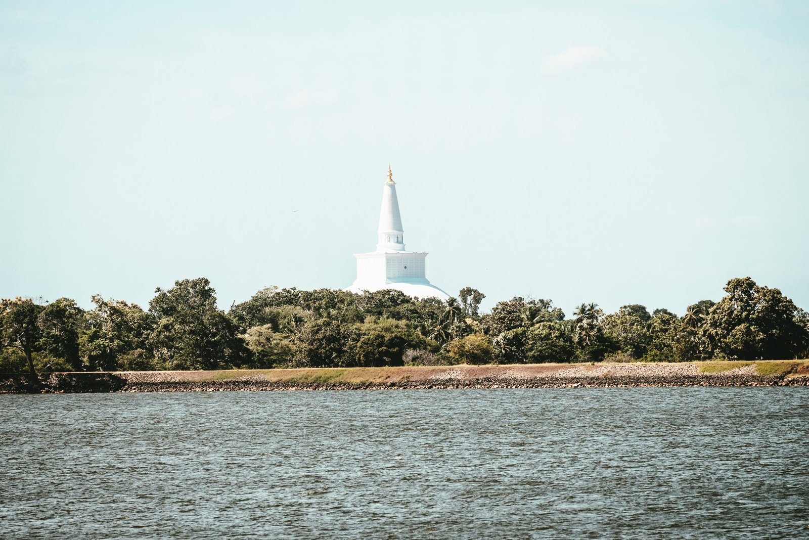 white lighthouse on green grass field near body of water during daytime